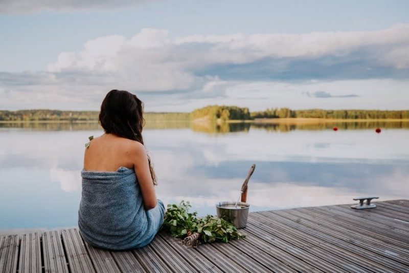 Vrouw geniet na van de sauna aan een meer in Finland