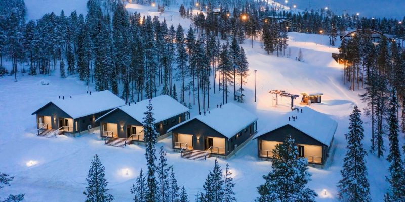 Pyhä in de winter met verlichte cabins met op de achtergrond skiliften en pistes