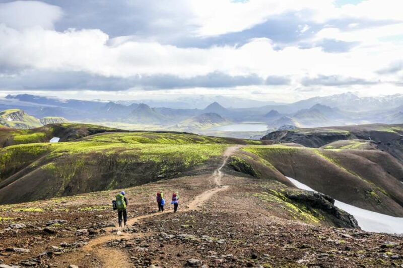 Mensen wandelen tijdens een groepsreis met Nordic door een gebied met groene bergen en vulkanen in IJsland