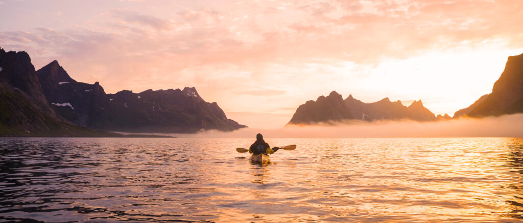 A sea kayaker taking a break from paddling at midnight in Lofoten ( 24 hour daylight ).